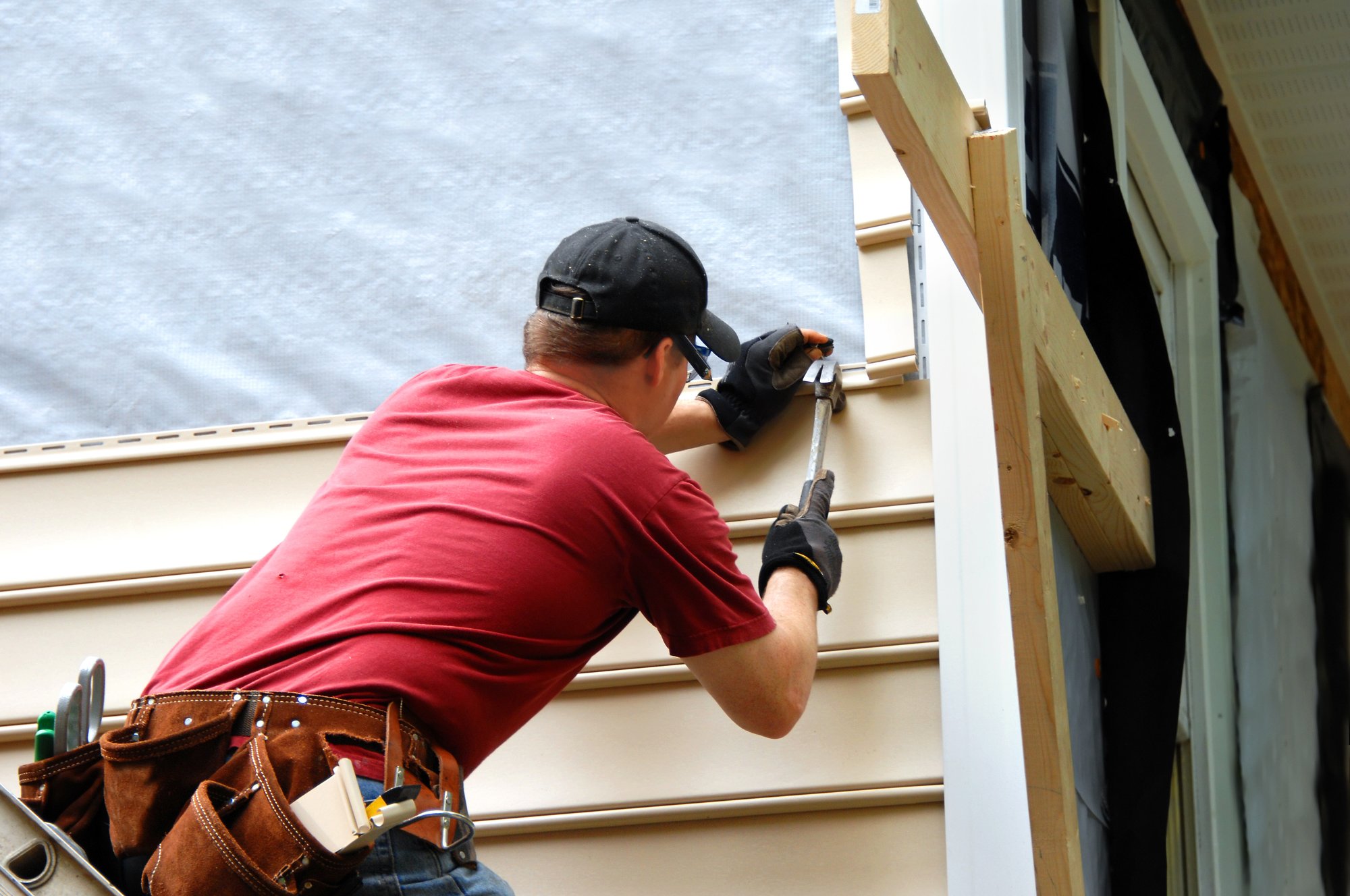 man repairing siding of home