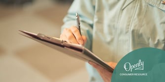A man writes on a clipboard held in his other hand