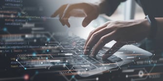 Two hands type on a keyboard with a transparent motherboard overlaid over the image. 