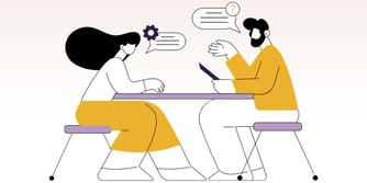 Two people sit at a table having a discussion. 