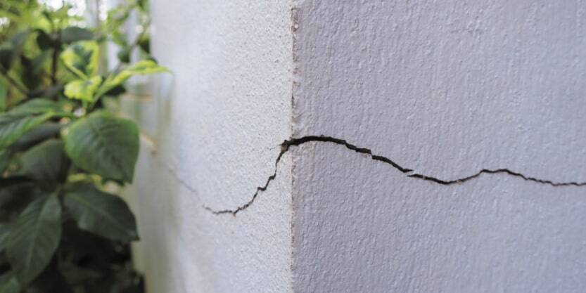 A crack bisects the foundation of a white structure.